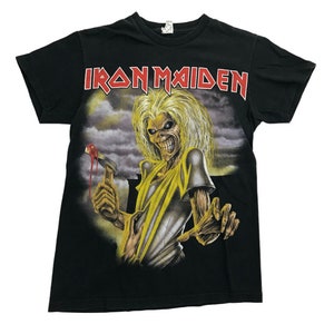 May include: Black t-shirt with a graphic print of a yellow skeletal figure holding a hammer with blood dripping from it. The text "IRON MAIDEN" is printed in red above the figure.