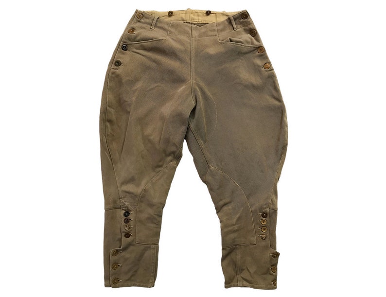 May include: A pair of brown riding breeches with button closures on the sides and at the bottom of the legs.