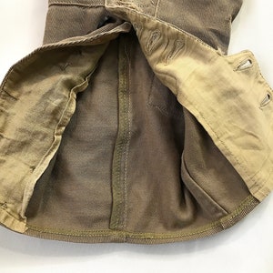 May include: A brown corduroy jacket with a tan lining. The jacket is unbuttoned and the lining is visible. The jacket has a seam down the back and a button closure at the neck.