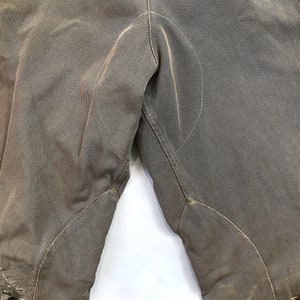 May include: A pair of brown riding breeches with knee patches. The breeches are made of a thick, durable fabric and have a classic design.