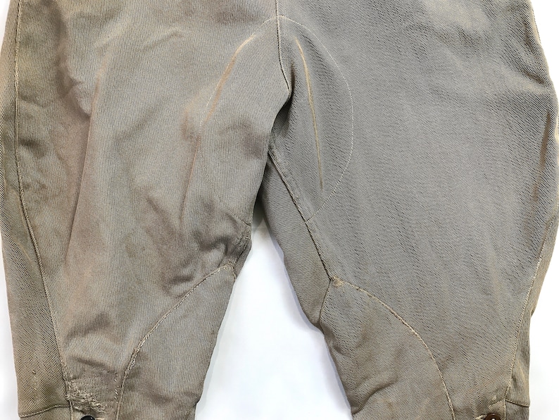 May include: A pair of brown riding breeches with knee patches. The breeches are made of a thick, durable fabric and have a classic design.