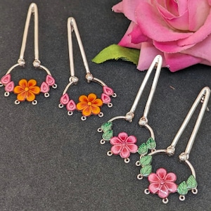 May include: Three pairs of silver dangle earrings with floral designs. The earrings feature a variety of colors, including pink, orange, and green.
