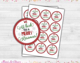 May include: A sheet of circular stickers featuring a red dotted border and the text "WE Whisk YOU A MERRY Kissmas!" in green and red script. The design includes small red whisk icons and light gray snowflake patterns on a white background.