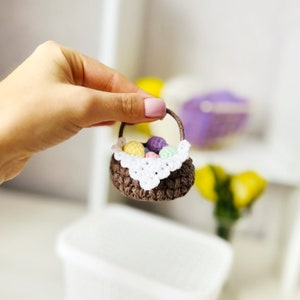 May include: A small brown crocheted basket with a white crocheted doily and filled with colorful crocheted Easter eggs.