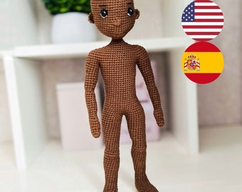 Könnte beinhalten: Eine braune gehäkelte Puppe mit neutralem Gesichtsausdruck. Die Puppe hat schwarze Augen und eine braune Nase. Die Puppe steht auf einer weißen Oberfläche.