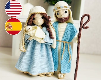 May include: Crocheted figures of the Holy Family, Mary, Joseph, and baby Jesus. Mary is wearing a blue dress with a gold trim and a white head covering. Joseph is wearing a blue robe with a gold sash and a brown beard. Baby Jesus is wrapped in a white blanket. The figures are standing on a white surface.