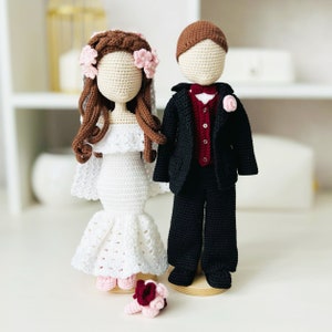 Puede incluir: Muñecas de crochet de novia y novio vestidas de blanco y negro. La novia lleva un vestido blanco con ribete de encaje y una corona de flores. El novio lleva un traje negro con un chaleco rojo y una pajarita.