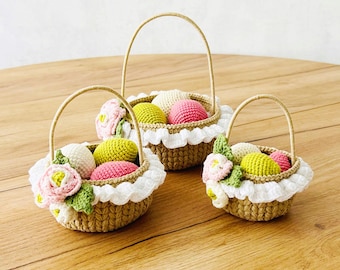 May include: Three handmade crochet baskets with handles, each filled with colorful crochet eggs and floral accents. The baskets are brown with white lace trim and are arranged on a wooden surface.