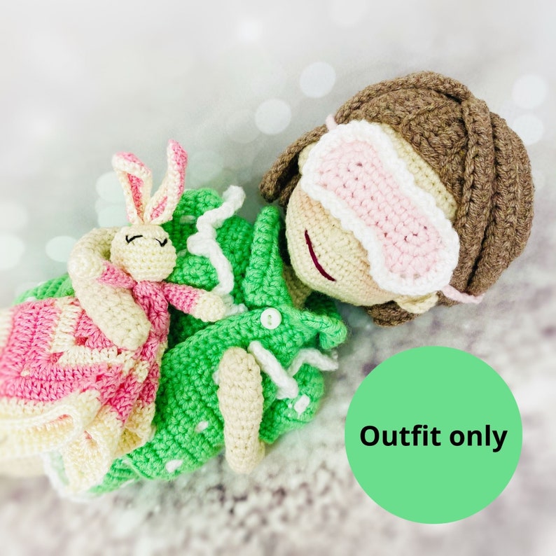 May include: Green and pink crocheted outfit for a doll, featuring a sleep mask and a small crocheted bunny. The outfit is labeled "Outfit only".
