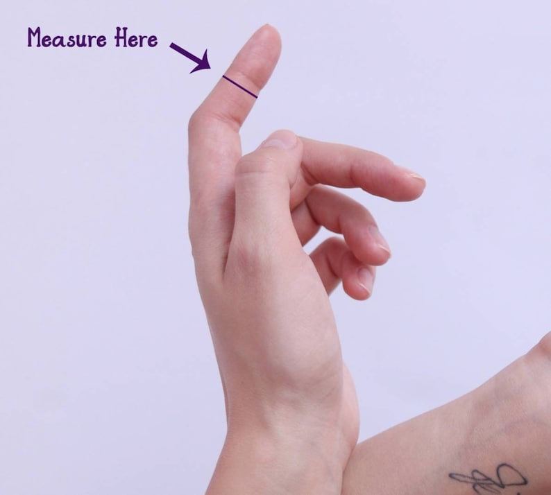 Puede incluir: Primer plano de una mano con un dedo extendido. Una l&iacute;nea negra se dibuja a trav&eacute;s del dedo, con el texto "Medir aqu&iacute;" y una flecha que apunta a la l&iacute;nea.