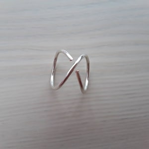 Puede incluir: Un anillo de plata con un dise&ntilde;o simple y retorcido. El anillo est&aacute; hecho de alambre fino y tiene un aspecto delicado y minimalista.