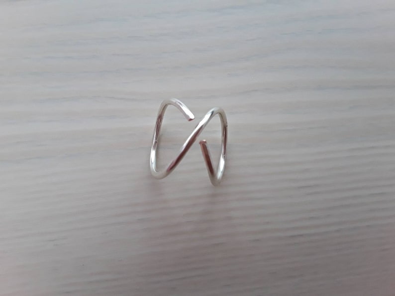 Puede incluir: Un anillo de plata con un dise&ntilde;o simple y retorcido. El anillo est&aacute; hecho de alambre fino y tiene un aspecto delicado y minimalista.
