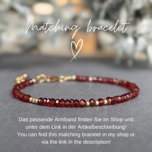 Op de afbeelding: Een delicate armband met kleine, gefacetteerde rode kralen en goudkleurige accenten. De armband is geregen op een dun, flexibel koord en heeft een gouden sluiting. Tekst op de afbeelding luidt "Matching bracelet".