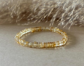 May include: A circular bracelet composed of small, translucent yellow and clear disc-shaped beads. The beads are strung together in a continuous loop, featuring varying shades of amber, gold, and pale yellow throughout the entire piece.