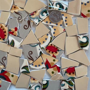 May include: A collection of ceramic tile pieces in various shapes and sizes. The tiles feature a floral pattern with red, yellow, blue, and green colors on a white background. Some tiles are plain beige.