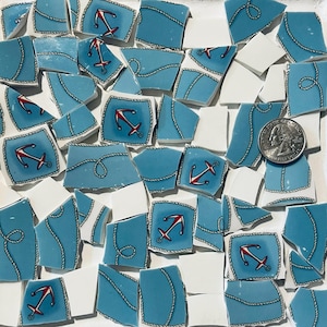 Könnte beinhalten: Eine Sammlung zerbrochener Keramikfliesen in Blau- und Weißtönen. Die blauen Fliesen weisen nautische Designs auf, darunter rote Anker und Seildetails. Eine Münze ist als Größenreferenz enthalten. Ideal für Mosaikkunstprojekte.