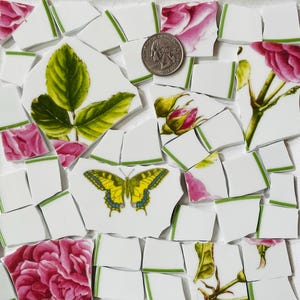 May include: A mosaic of broken ceramic pieces featuring floral and butterfly designs. The fragments include images of pink roses, green leaves, and a yellow butterfly. A quarter coin is included for size reference.