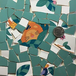 May include: A collection of green, white, and orange ceramic mosaic tiles with a lion, leaves, and flowers. The tiles are irregular in shape and size, and some have a glossy finish.