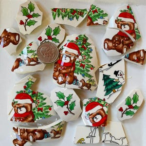 May include: A collection of broken ceramic pieces featuring Christmas-themed designs. The fragments display images of teddy bears in Santa hats, Christmas trees, holly, and gift boxes. The color palette includes red, green, brown, and white.