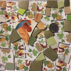 May include: A collection of broken ceramic tiles with a green, white, and brown floral pattern. The tiles are arranged in a random pattern and include a single tile with a rooster illustration.