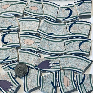 May include: A collection of broken ceramic tiles with a blue, green, and white striped pattern. Some tiles feature pink and purple floral designs.