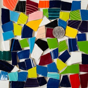 May include: A collection of colorful ceramic tile pieces in various shapes and sizes. The tiles are arranged in a random pattern and include shades of blue, green, red, yellow, and white.