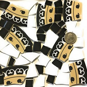 May include: A mosaic tile design featuring broken pieces in black, white, and tan. The tan pieces have a decorative black pattern. A quarter is included for size reference.