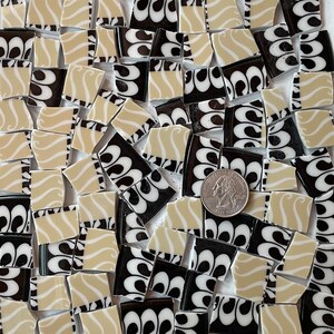 May include: A collection of black and white mosaic tiles with a swirl pattern. The tiles are various sizes and shapes. A US quarter is included for scale.
