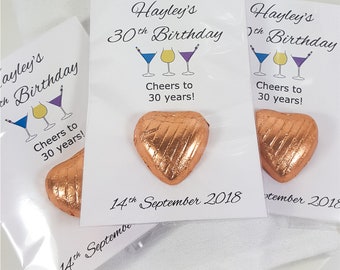 May include: Three heart-shaped chocolates wrapped in copper foil, each attached to a white card. The cards feature the text Hayley's 30th Birthday, Cheers to 30 years!, and 14th September 2018, along with illustrations of three colorful cocktail glasses.