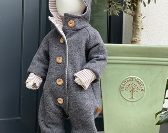 May include: A gray hooded baby jumpsuit with a white and pink striped lining. The jumpsuit has a pointed hood and button closures. The jumpsuit is being modeled on a white mannequin.
