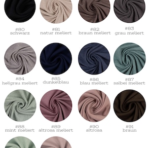 May include: A chart of jersey fabric swatches in various colors and textures, including black, natural, brown, gray, blue, mint, pink, and brown. The swatches are labeled with numbers and names, such as "schwarz" (black), "natur meliert" (natural melange), and "braun meliert" (brown melange).