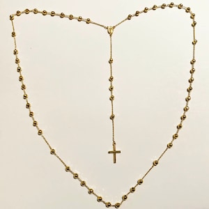 May include: A gold-toned rosary necklace with a small cross pendant. The necklace is made of small, round beads.