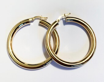 May include: A pair of gold hoop earrings. The earrings are simple and elegant, with a smooth, polished finish.