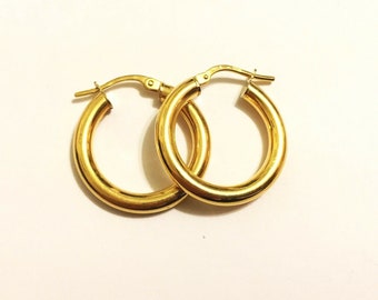 May include: A pair of gold hoop earrings. The earrings are simple and classic, with a smooth, polished finish.