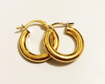May include: A pair of gold hoop earrings. The earrings are simple and classic, with a smooth, polished finish.
