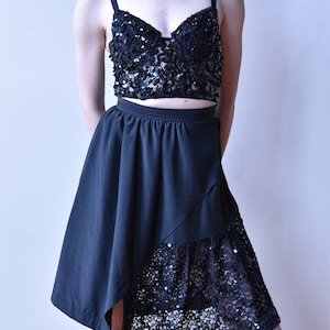 May include: Black sequined crop top with spaghetti straps and a matching black skirt. The skirt has an asymmetrical design with a sequined lace panel. The outfit is a two-piece set, perfect for a special occasion.
