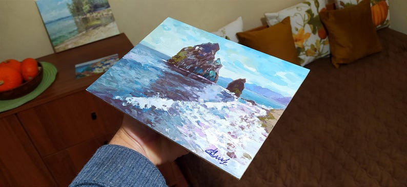May include: A painting of a seascape with two rocky islands in the foreground. The water is a deep blue with white foam crashing against the rocks. The sky is a light blue with white clouds. The painting is signed "Chust" in the lower right corner.