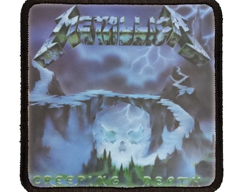 May include: A black and white patch with the words "Metallica" and "Creeping Death" in a stylized font. The patch features a skull with lightning bolts and a mountain range in the background.