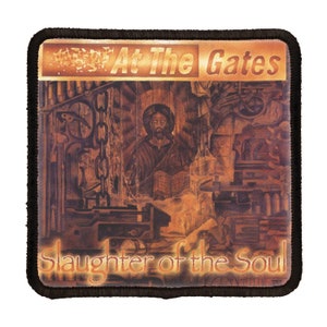 Puede incluir: Un parche bordado marrón y dorado con el texto "At The Gates" y "Slaughter of the Soul" en una fuente estilizada. El parche presenta una pintura de un hombre con barba y cabello largo, vistiendo una túnica, sentado en un trono.