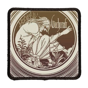 May include: A brown and white embroidered patch with a circular design featuring a figure sitting in a field of grass. The text "Witchcraft" is printed in white on the patch.