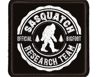 May include: Black and white patch with a distressed, circular design. The design features the text "Sasquatch Official Bigfoot Research Team" with a silhouette of Bigfoot walking inside the circle.