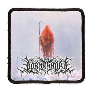 May include: A black and white embroidered patch featuring the band name "LORD GORE" in a gothic font. The patch depicts a hooded figure in a red robe holding a scythe, standing in a snowy landscape.