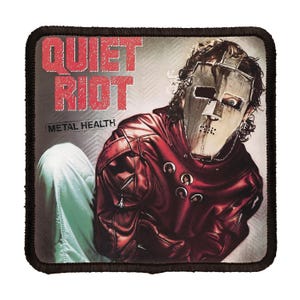 May include: A red, white and black patch with the words "Quiet Riot" and "Metal Health" in red. A person wearing a red leather jacket and a metal mask is pictured on the patch.