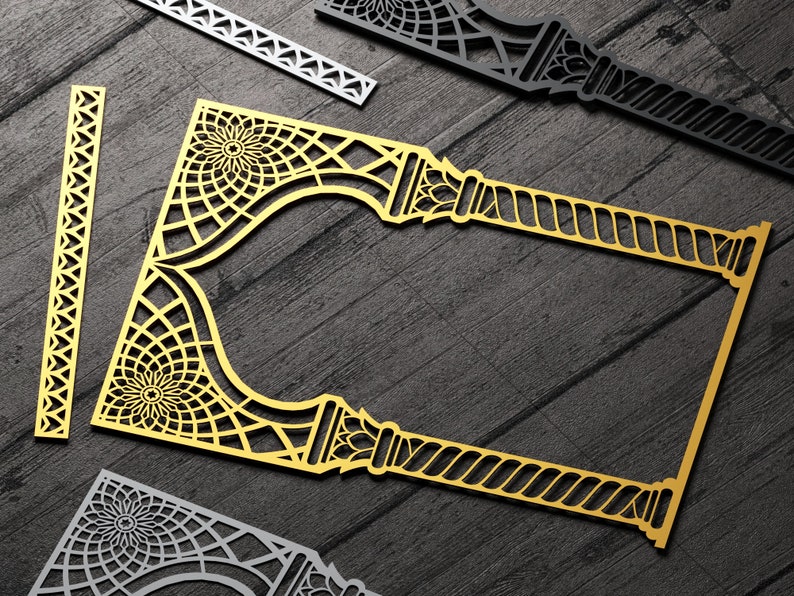 May include: A gold decorative frame with intricate geometric patterns and a rope-like design. The frame is made of thin metal and has a cutout design. The frame is on a dark wood background.