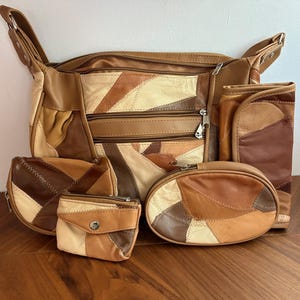 May include: A set of four bags featuring a patchwork design in various shades of brown, tan, and cream. The collection includes a large shoulder bag with multiple zippered compartments, a rectangular wallet, a small coin purse, and an oval pouch.