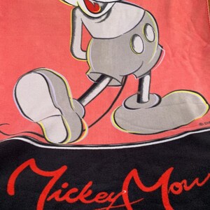 Może przedstawiać: Czerwony i czarny ręcznik Mickey Mouse z dużą ilustracją Myszki Miki. Ręcznik ma napis "Mickey Mouse" w czerwonym skrypcie na dole, klasyczny design Disneya.