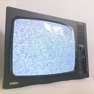 May include: A black and silver vintage television with a static screen and the word "Iskra" on the bottom left corner.