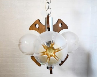 May include: A vintage mid-century modern chandelier with a chrome and wood design. The light fixture features three frosted glass globes and a central, multi-faceted globe with a gold-coloured centre. The chandelier is suspended from a chain.