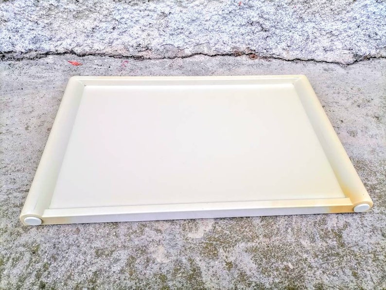 Może przedstawiać: Biała plastikowa taca do serwowania z zaokrąglonymi krawędziami. Taca ma gładką powierzchnię i idealnie nadaje się do serwowania jedzenia lub napoj&oacute;w.