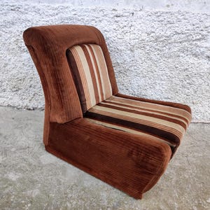 May include: A brown corduroy armchair with a striped cushion. The chair has a curved back and a wide seat.